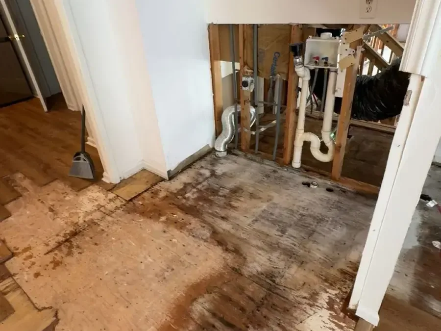 Wall opened around plumbing above a stained subfloor