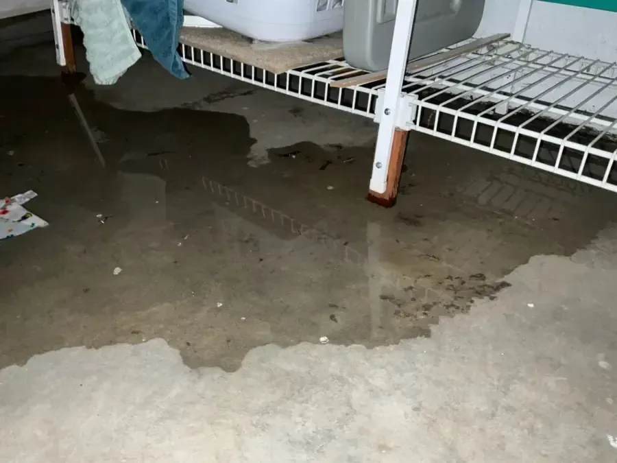 Standing water on a concrete floor beneath storage shelving