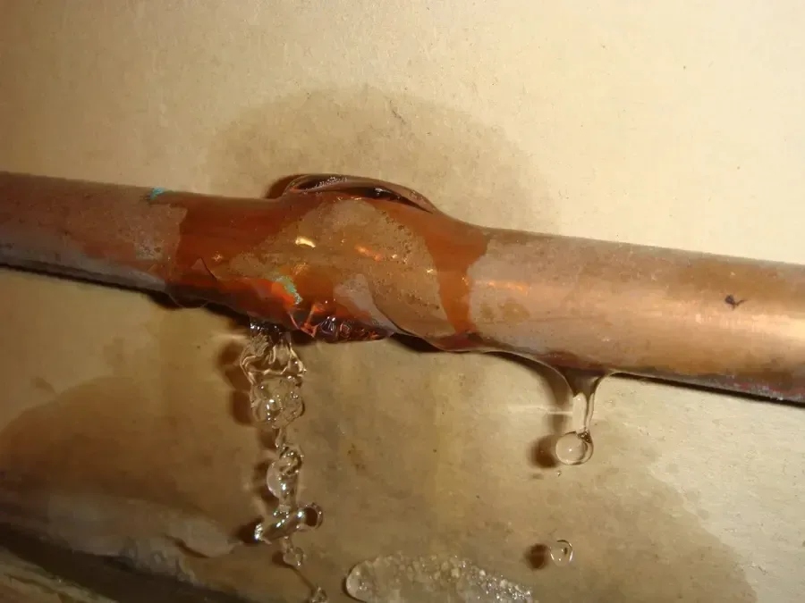 Water dripping from a split copper pipe during a burst pipe leak