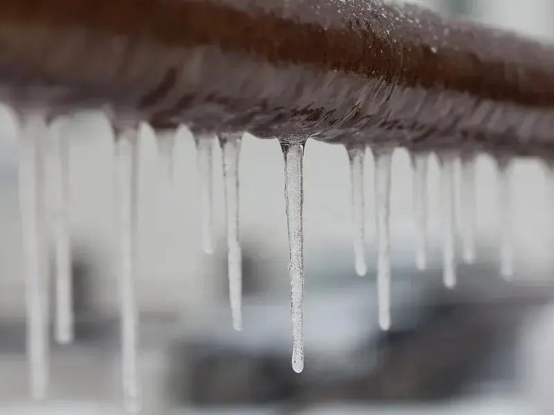 Icicles hanging from an exposed pipe during a hard freeze